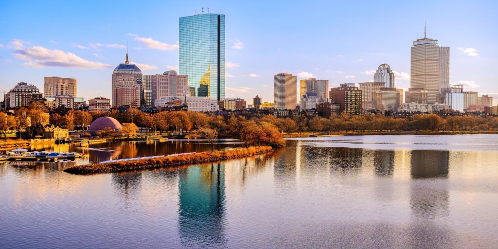 Boston City Skyline over the Charles River in Massachusetts, USA. A tranquil riverscape of Back Bay with golden illuminated wintery foliage in New England.